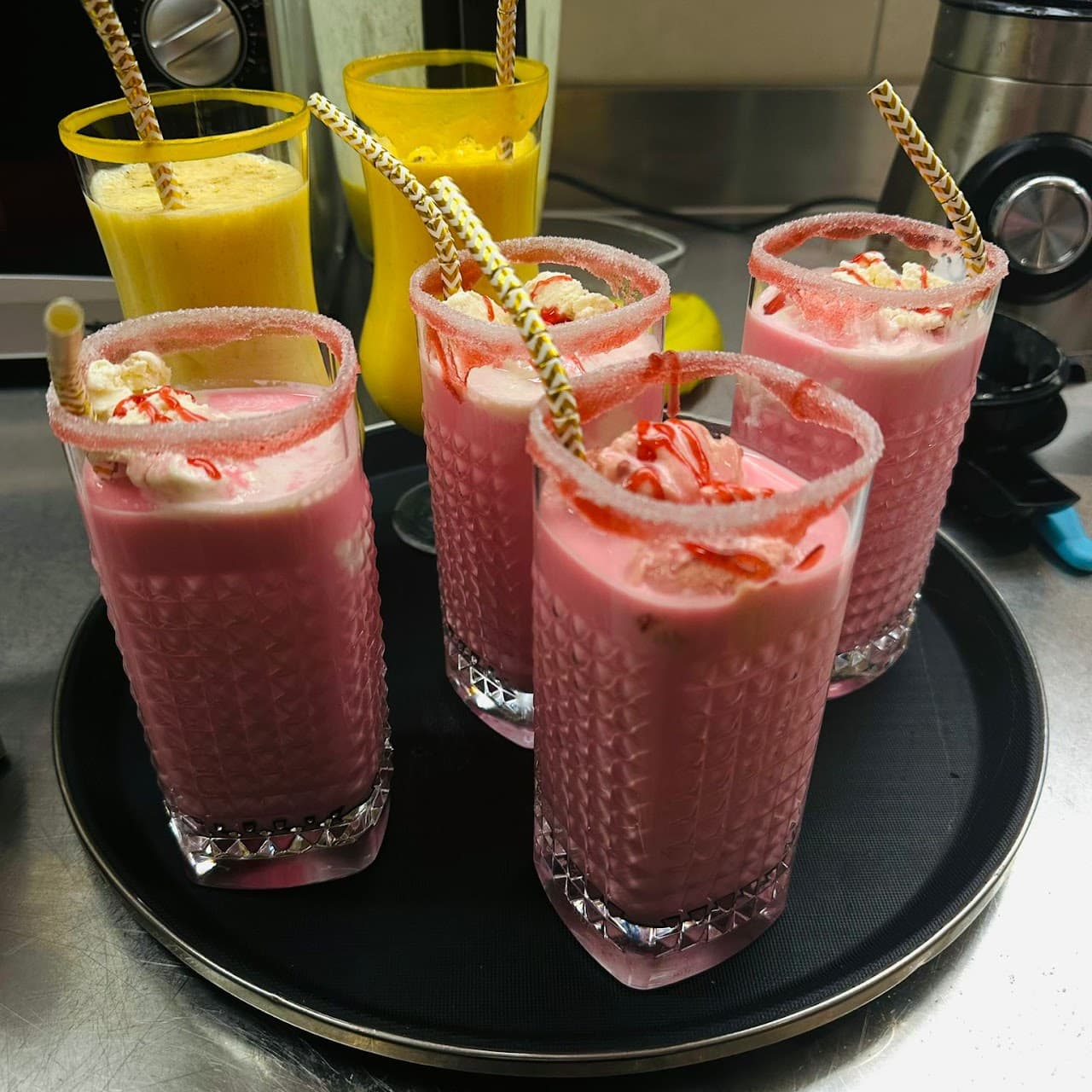 Pinke Sarbat-Drinks und Mango-Lassi auf einem Serviertablett